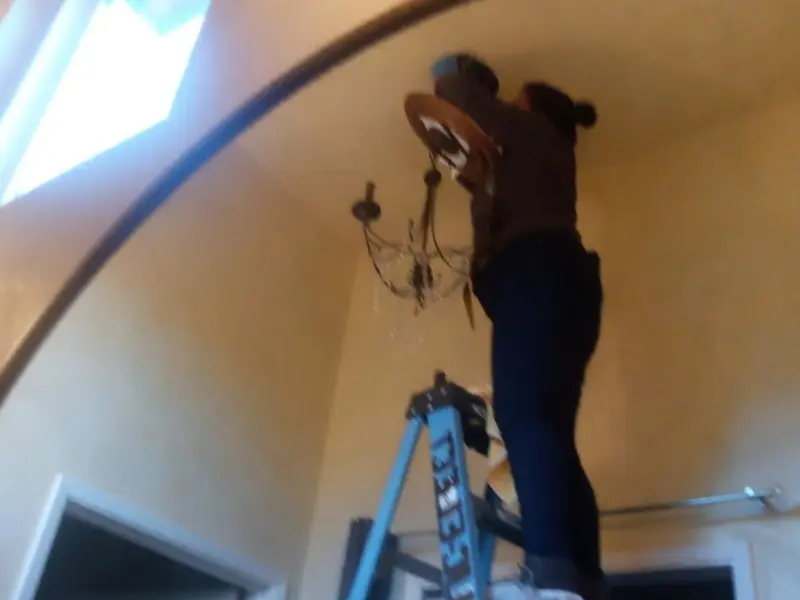 Electrician installing a chandelier in a Lakeside residence